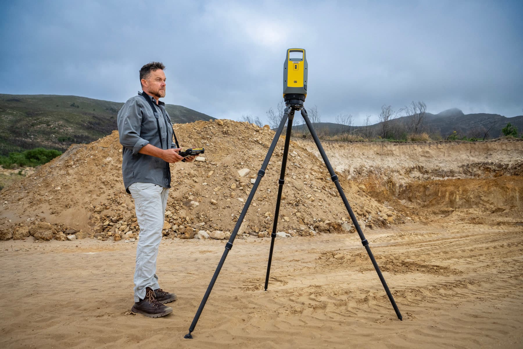 A GeoSurv surveyor setting up a Trimble X7 laser scanner on a tripod at a quarry.