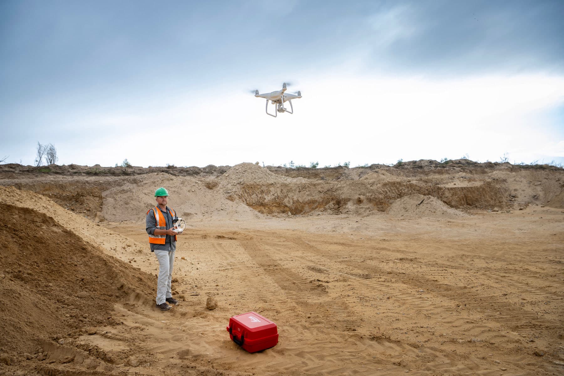 A GeoSurv surveyor flying a DJI drone over an excavated sand quarry.